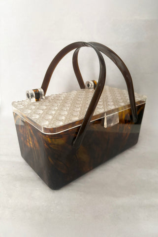 Vertical perspective view of 1950s vintage tortoiseshell brown marbled Lucite box bag with clear faceted lid.