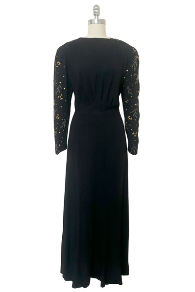 Front view of 1930s vintage black rayon crepe evening gown with statement sleeves beaded with glass beads and brass sequins, small to medium.