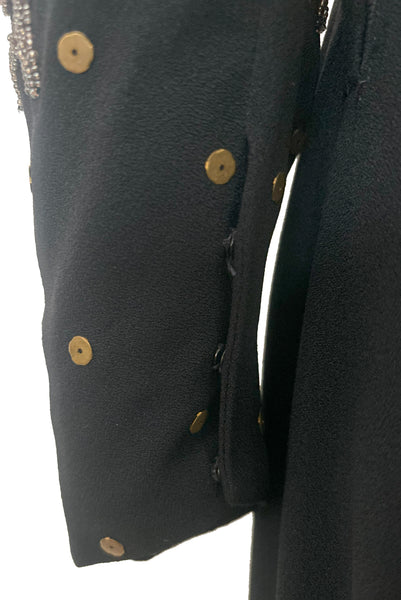 Sleeve detail view of 1930s vintage black rayon crepe evening gown with statement sleeves beaded with glass beads and brass sequins, small to medium. Showing the brass leaves and sequins, and pewter gray glass beaded leaves, and snap closure cuffs.