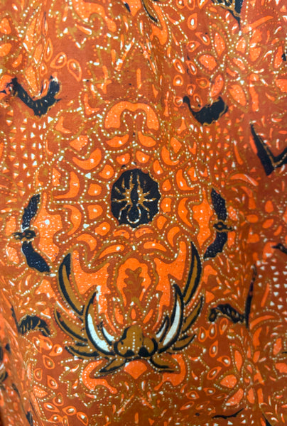 Fabric detail view of 1970s vintage orange and black Halloween bat and spider wax print cotton maxi dress with halter neckline, extra small to small.