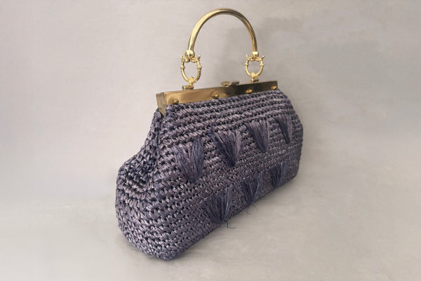 Horizontal perspective view of 1950s periwinkle blue crochet raffia straw handbag with ornate gold tone metal handle, by Simon, made in Japan.