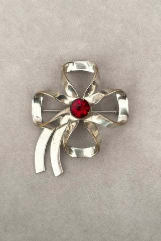 Vertical front view of 1950s vintage silver tone and round red rhinestone bow/ribbon brooch.