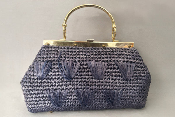 Horizontal front view of 1950s periwinkle blue crochet raffia straw handbag with ornate gold tone metal handle, by Simon, made in Japan.