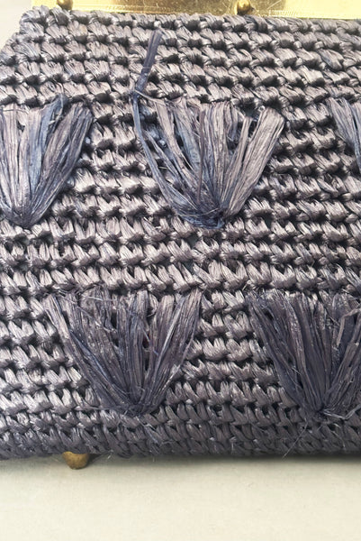 Detail view of 1950s periwinkle blue crochet raffia straw handbag with ornate gold tone metal handle, by Simon, made in Japan. Showing a close-up of some loose raffia on the front of the purse.