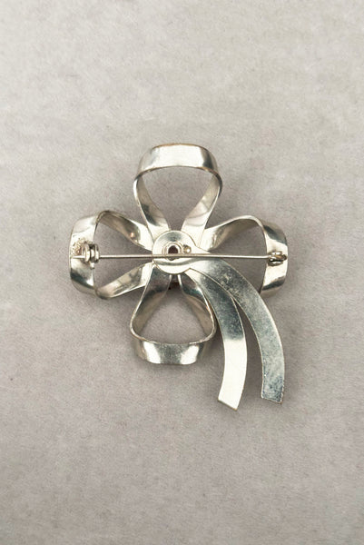 Vertical back view of 1950s vintage silver tone and round red rhinestone bow/ribbon brooch.