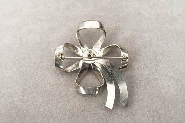 Horizontal back view of 1950s vintage silver tone and round red rhinestone bow/ribbon brooch.