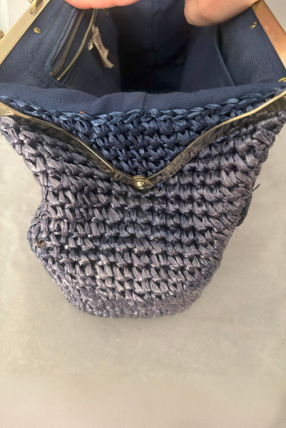 Detail view of 1950s periwinkle blue crochet raffia straw handbag with ornate gold tone metal handle, by Simon, made in Japan. Showing the open bag with the original color straw on the inside.