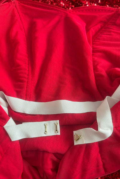 Interior detail view of red stretch velvet, sequin embellished dress with satin straps, sweetheart neckline, cold shoulder short sleeves, princess seamed bodice, and pencil skirt.  Showing the cream petersham ribbon waist stay with gold tone hooks. 