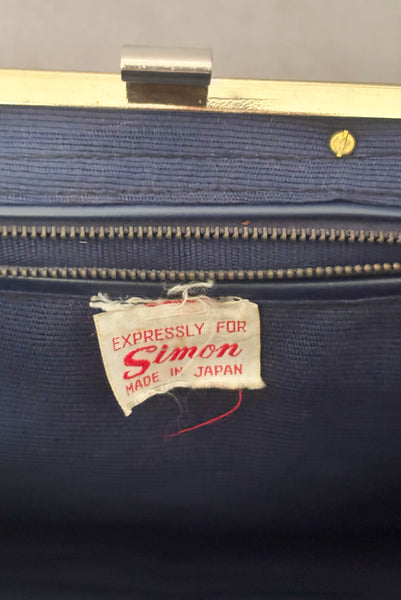 Detail view of 1950s periwinkle blue crochet raffia straw handbag with ornate gold tone metal handle, by Simon, made in Japan. Showing the Simon label.