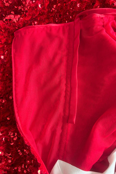 Interior detail view of red stretch velvet, sequin embellished dress with satin straps, sweetheart neckline, cold shoulder short sleeves, princess seamed bodice, and pencil skirt.  Showing the red satin bias cut straps sewn down on the inside that can be freed to tie behind the neck as a halter. 