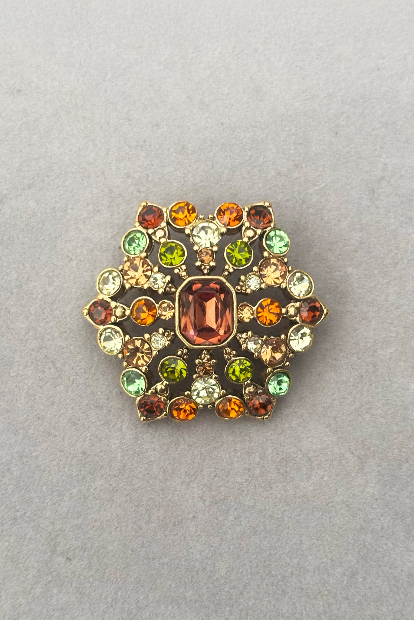 Vertical front view of 2000s vintage y2k autumnal brown, orange, green, and yellow rhinestone hexagonal brooch, by Liz Claiborne.