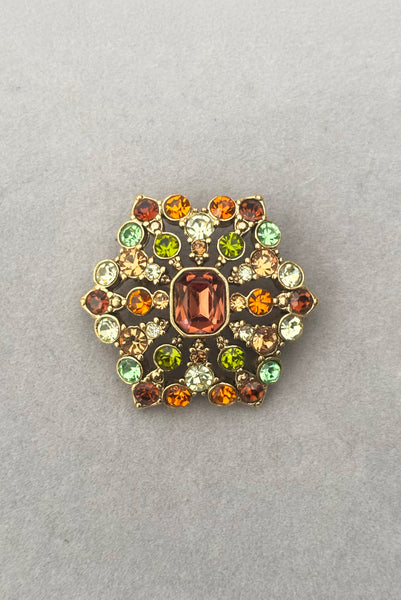 Vertical front view of 2000s vintage y2k autumnal brown, orange, green, and yellow rhinestone hexagonal brooch, by Liz Claiborne.