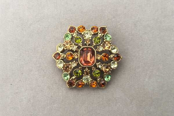 Horizontal front view of 2000s vintage y2k autumnal brown, orange, green, and yellow rhinestone hexagonal brooch, by Liz Claiborne.