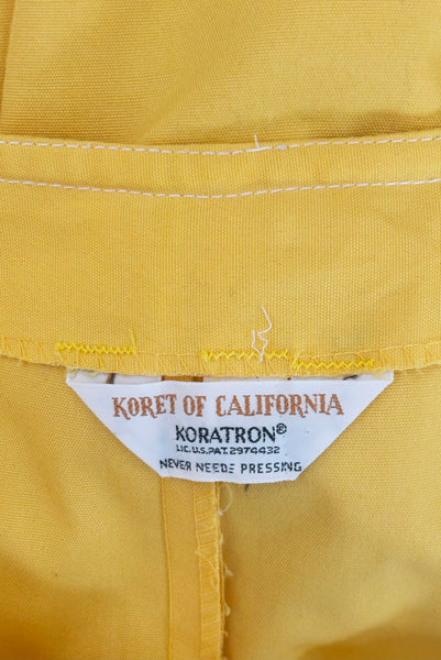 Interior detail view of 1960s vintage Koret of California Koratron yellow fabric skort with white plastic buttons, size medium to large. Showing a close up of the three white buttons on the front flap closure.  Showing the Koret of California Koratron label.