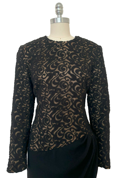 Front bodice view of 1990s vintage Balmain Ivoire long sleeve nude look black wool lace cocktail dress with draped wool crepe skirt, small to medium. Showing the swirl pattern black wool lace with beige lining for a nude look.