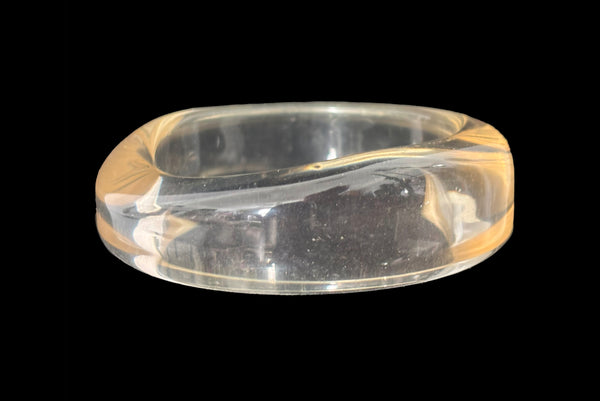 Horizontal front view of 1980s vintage clear Lucite asymmetrical bangle bracelet.