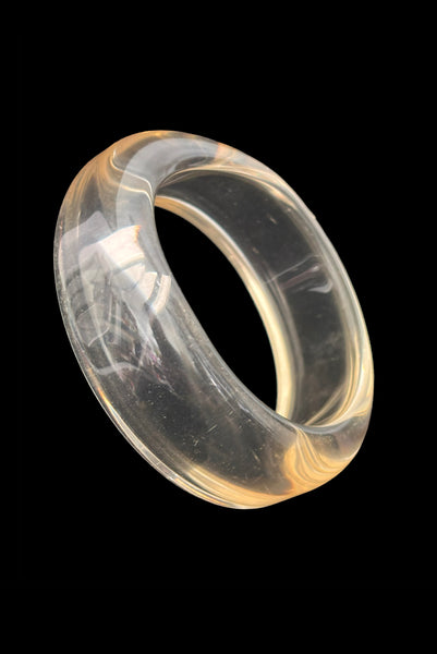 Vertical perspective view of 1980s vintage clear Lucite asymmetrical bangle bracelet.