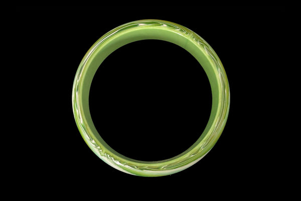 Horizontal top view of 1960s vintage green, chartreuse, and white feathered Lucite plastic domed bangle bracelet.