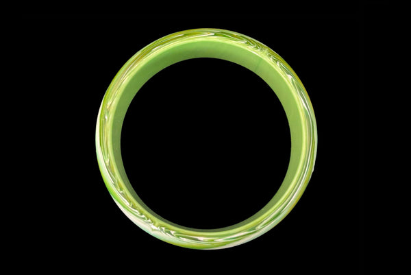 Horizontal bottom view of 1960s vintage green, chartreuse, and white feathered Lucite plastic domed bangle bracelet.