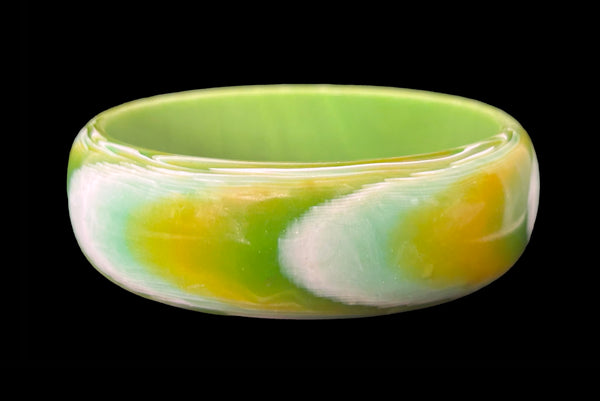 Horizontal front view of 1960s vintage green, chartreuse, and white feathered Lucite plastic domed bangle bracelet.