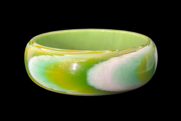 Horizontal back view of 1960s vintage green, chartreuse, and white feathered Lucite plastic domed bangle bracelet.