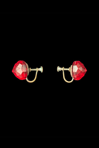 Vertical side view of 1930s vintage flame orange faceted glass round screw back earrings.