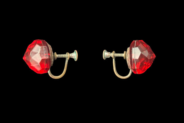 Horizontal side view of 1930s vintage flame orange faceted glass round screw back earrings.