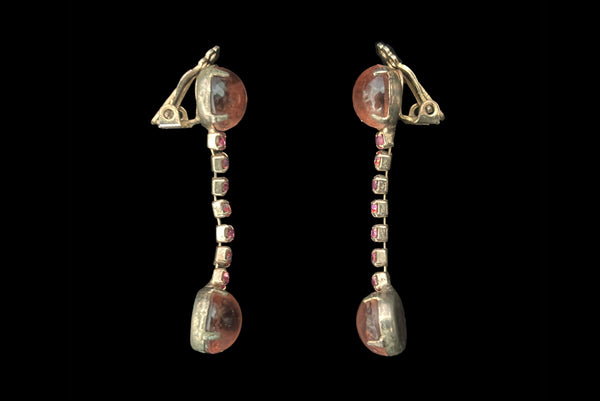 Horizontal side view of 1950s vintage round pink glass cabochon top and drop iridescent pink rhinestone clip-on earrings.