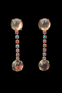 Vertical front view of 1950s vintage round pink glass cabochon top and drop iridescent pink rhinestone clip-on earrings.