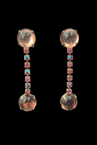 Vertical front view of 1950s vintage round pink glass cabochon top and drop iridescent pink rhinestone clip-on earrings.