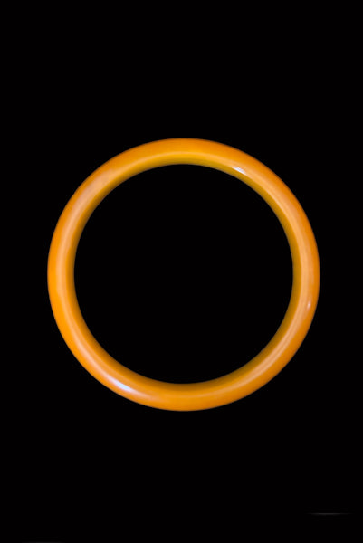 Vertical top view of 1940s vintage egg yolk and butterscotch mustard yellow marbled Bakelite domed bangle bracelet.