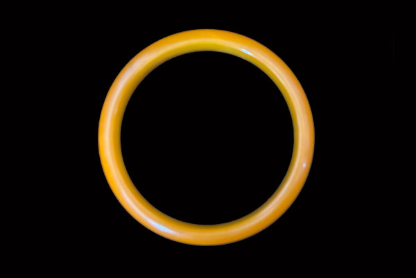 Horizontal top view of 1940s vintage egg yolk and butterscotch mustard yellow marbled Bakelite domed bangle bracelet.