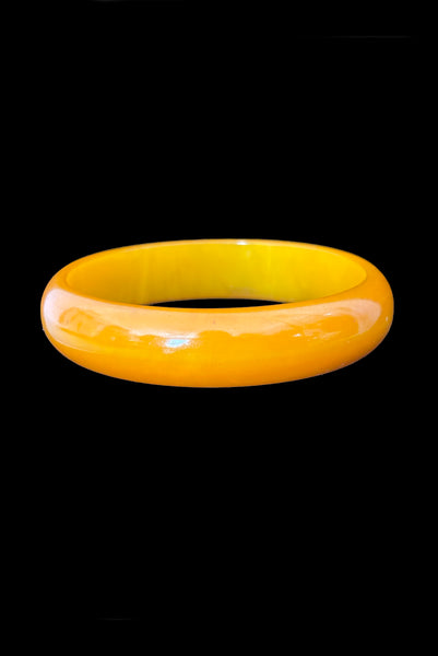 Vertical front view of 1940s vintage egg yolk and butterscotch mustard yellow marbled Bakelite domed bangle bracelet.