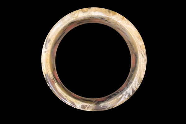 Horizontal top view of 1960s vintage artisan lime green, pink, and black inlaid checkerboard Lucite bangle bracelet on a translucent marbled beige base.