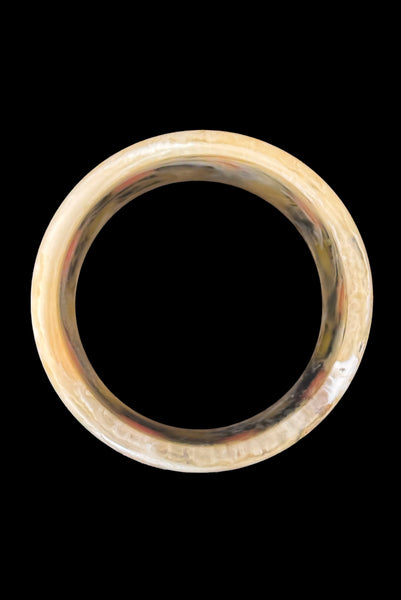 Vertical bottom view of 1960s vintage artisan lime green, pink, and black inlaid checkerboard Lucite bangle bracelet on a translucent marbled beige base.
