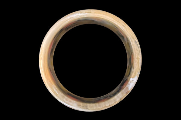 Horizontal bottom view of 1960s vintage artisan lime green, pink, and black inlaid checkerboard Lucite bangle bracelet on a translucent marbled beige base.