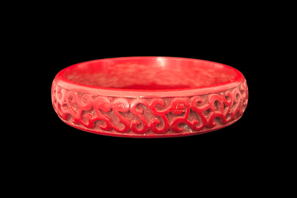 Horizontal front view of 1950s vintage red cinnabar scroll carved lacquered Asian bangle bracelet.