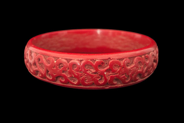 Horizontal front view of 1950s vintage red cinnabar scroll carved lacquered Asian bangle bracelet. Showing a close-up of the area where the carving isn't as fine.