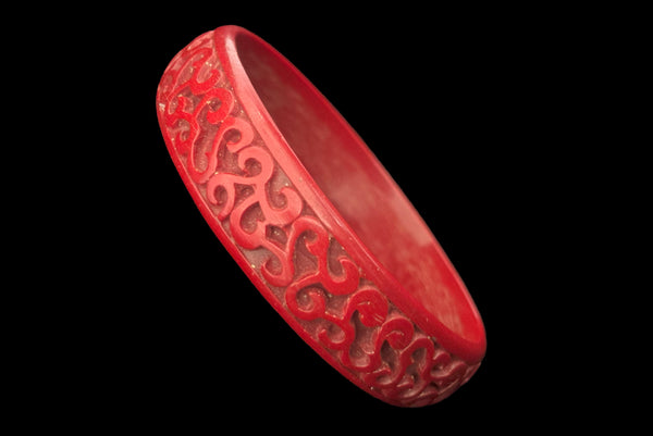 Horizontal perspective view of 1950s vintage red cinnabar scroll carved lacquered Asian bangle bracelet.