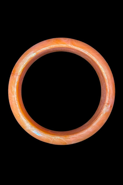 Vertical top view of 1980s iridescent orange and crackled orange and white plastic bangle bracelet set of two (2). Showing the iridescent domed bangle.
