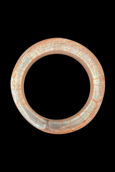 Vertical top view of 1980s iridescent orange and crackled orange and white plastic bangle bracelet set of two (2). Showing the asymmetrical orange and white crackled bangle.