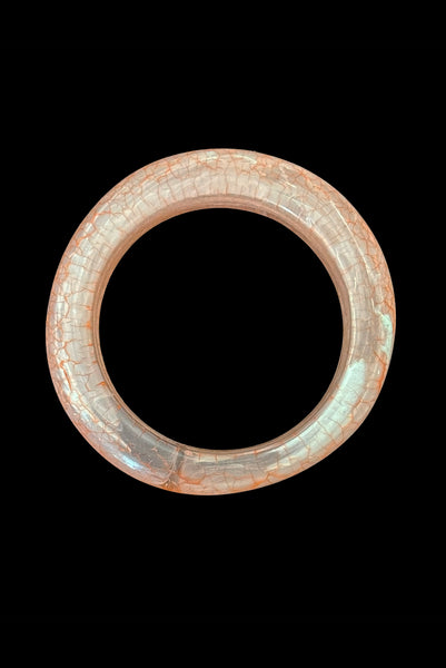 Vertical bottom view of 1980s iridescent orange and crackled orange and white plastic bangle bracelet set of two (2). Showing the asymmetrical orange and white crackled bangle.