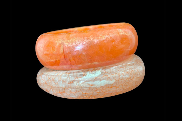 Horizontal front view of 1980s iridescent orange and crackled orange and white plastic bangle bracelet set of two (2).