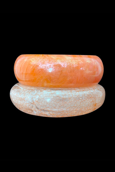 Vertical front view of 1980s iridescent orange and crackled orange and white plastic bangle bracelet set of two (2).