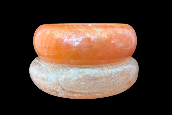Horizontal front view of 1980s iridescent orange and crackled orange and white plastic bangle bracelet set of two (2).