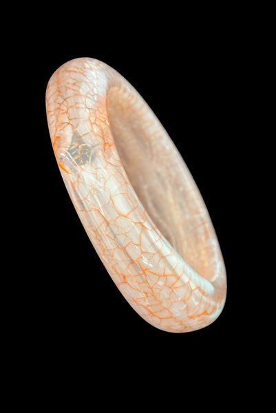 Vertical perspective view of 1980s iridescent orange and crackled orange and white plastic bangle bracelet set of two (2). Showing the asymmetrical orange and white crackled bangle.