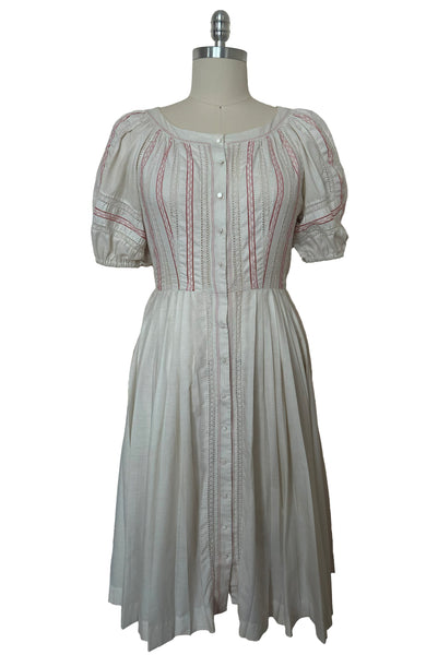 Front view of 1950s vintage white cotton scoop neck, button front, gathered half sleeve, pleated skirt peasant dress with red embroidery, size small to medium.