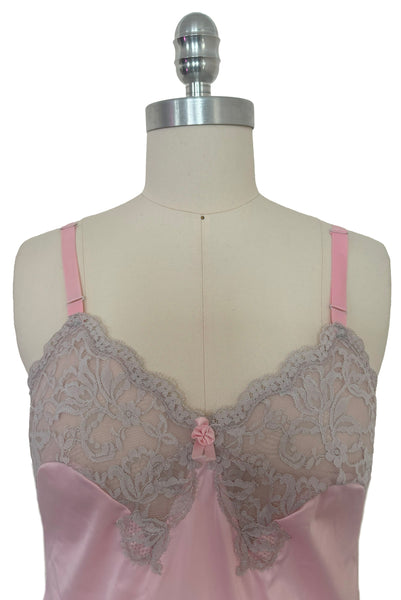 Bodice front view of 1960s vintage pale pink nylon and gray lace full slip, extra small to small. Showing the floral lace bust, adjustable pink satin ribbon straps, and ribbon rosette detail at the center.