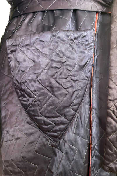 Detail view of 1940s purple satin quilted robe with pink satin lining by Sandora, medium to large. Showing the triangular pocket.