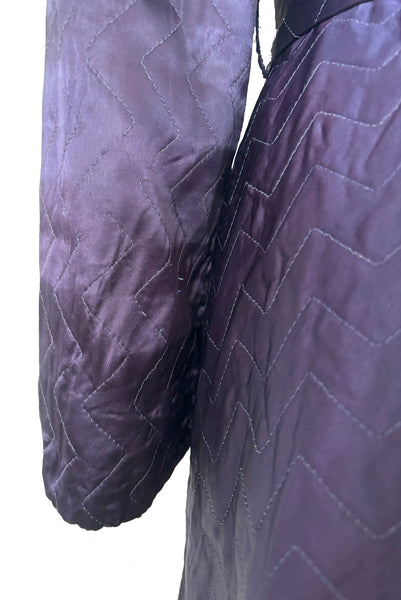 Detail view of 1940s purple satin quilted robe with pink satin lining by Sandora, medium to large. Showing some of the breaks in the quilting.